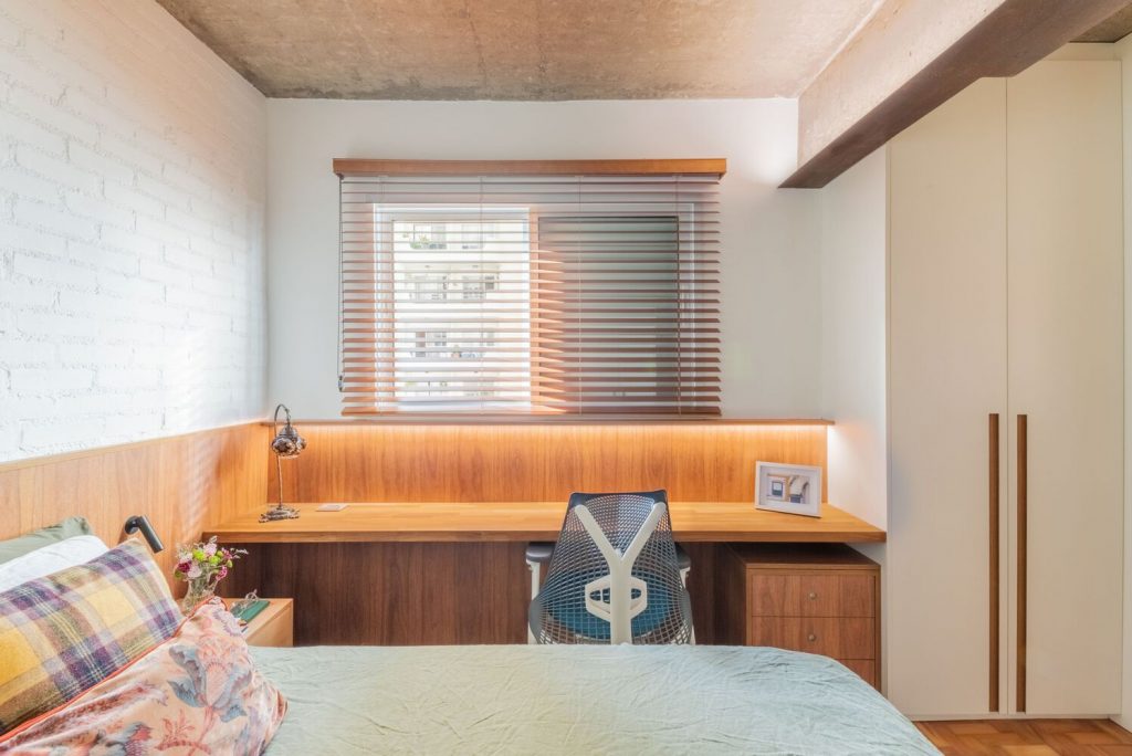 quarto com bancada de estudos em madeira e iluminação