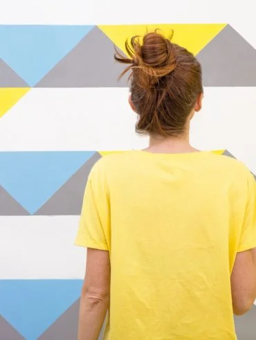 Interior Design. The girl paints the wall in geometric pattern.