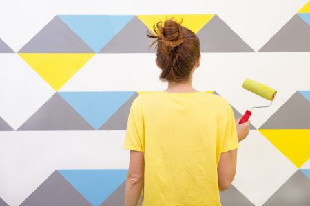 Interior Design. The girl paints the wall in geometric pattern.