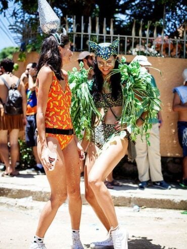 Duas mulheres de pele clara com fantasias maximalistas de Carnaval