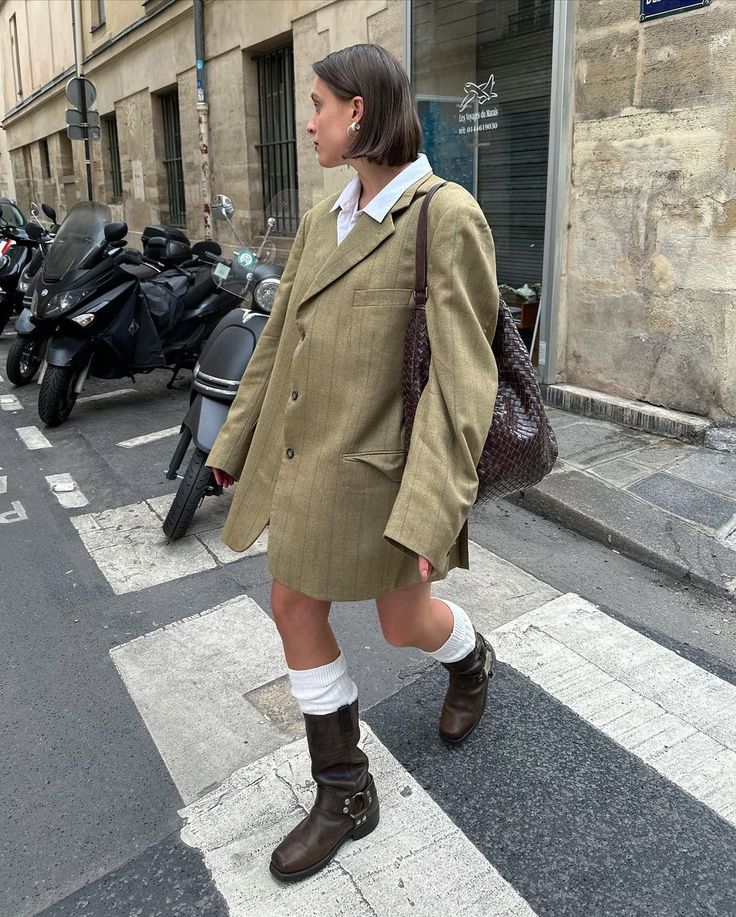 Mulher branca caminhando usando um blazer oversized e botas biker