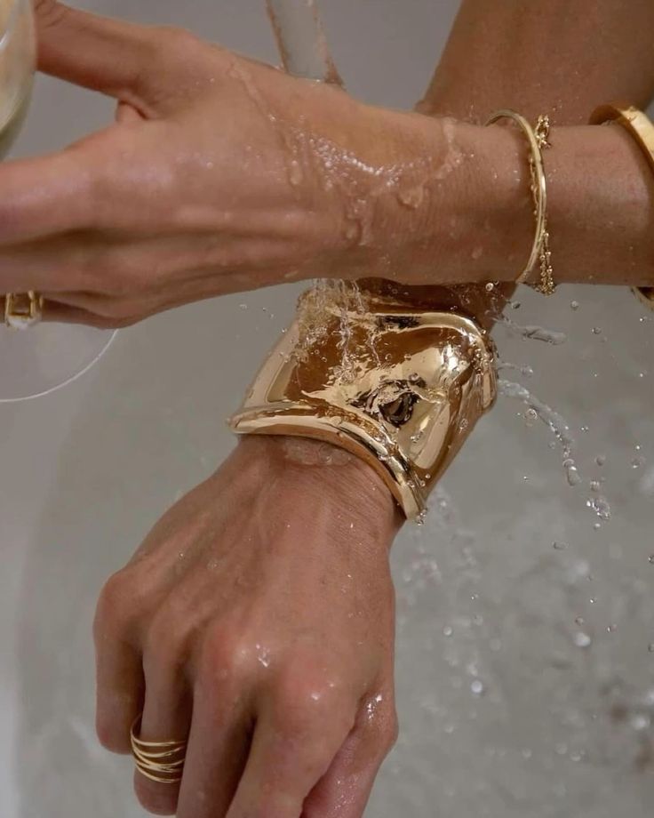Mãos brancas sobrepostas com braceletes dourados em ambas