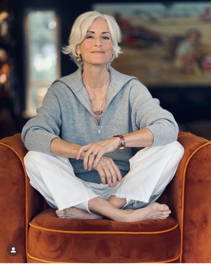 Mulher de 60 anos com blusa cinza e cabelo curto sentada