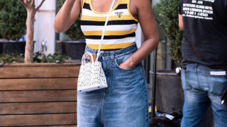 Foto aproximada onde vemos uma blusa listrada, bolsa tira colo e uma calça baggy