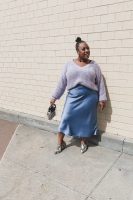 Modelo negra gorda, com saia de cetim azul e blusa em tricô lilás