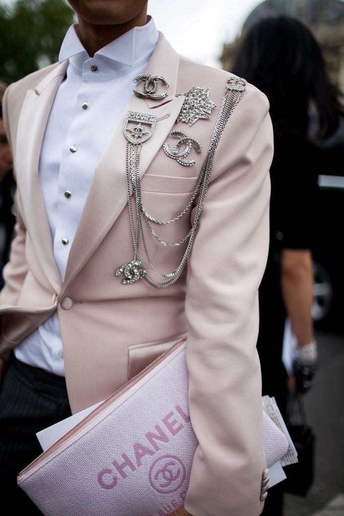 Pessoa vestindo um blazer rosa com broches da Chanel 