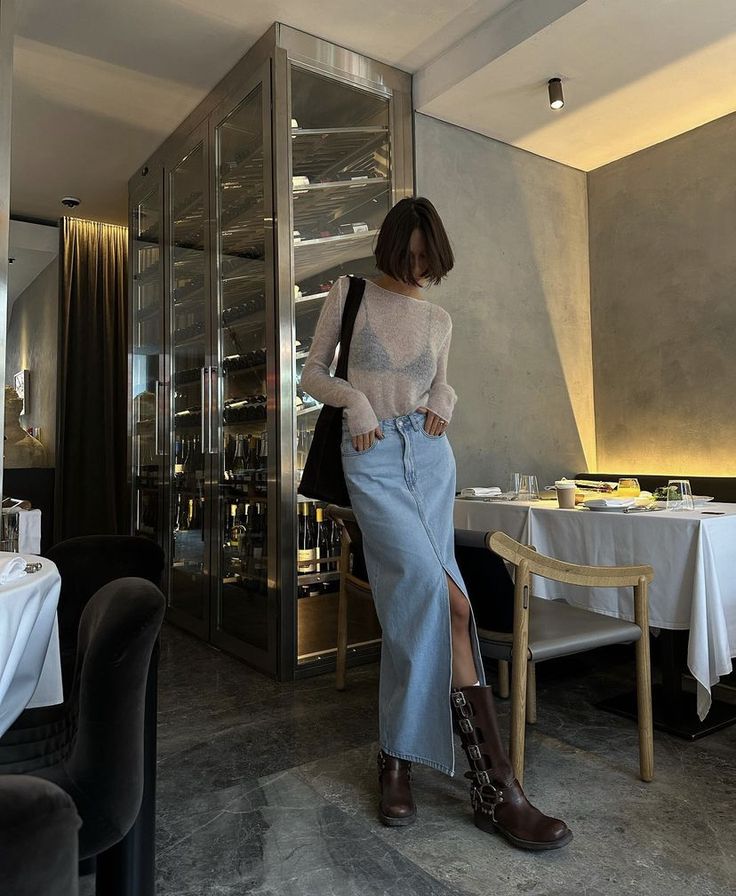 Mulher negra vestindo uma blusa de tule com saia longa jeans, e botas biker
