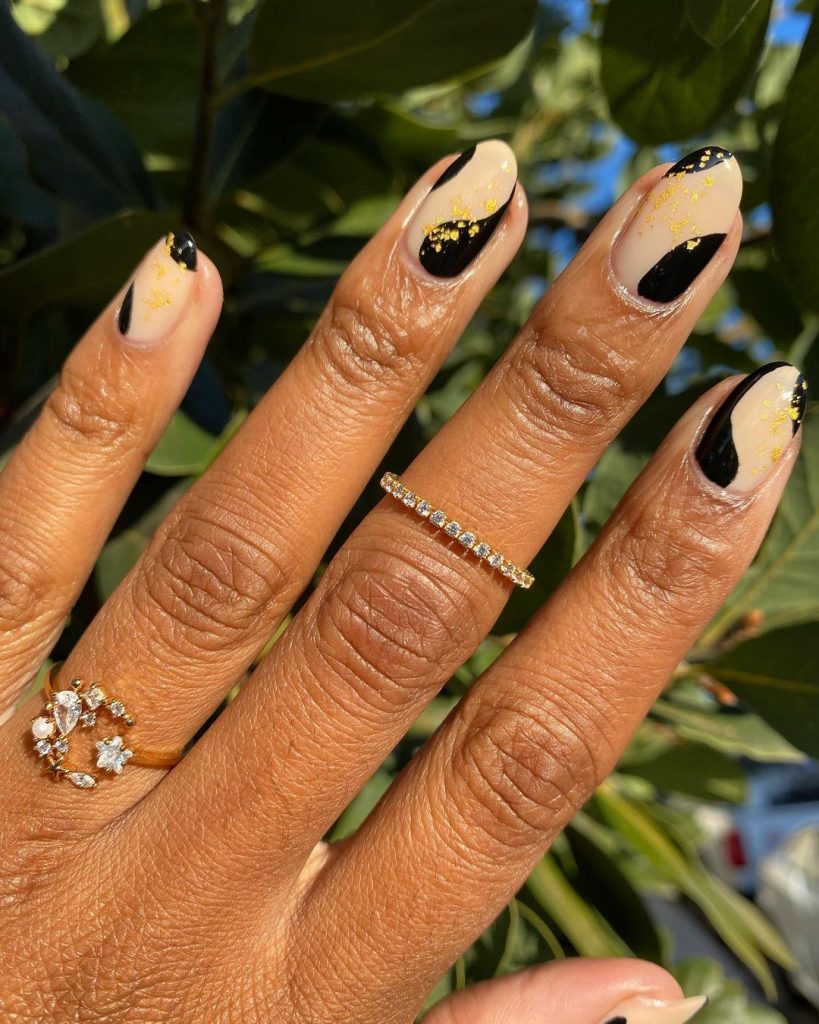 Mãe negra com anéis e unha com detalher orgânicos pretos, nudes e com folhas de ouro