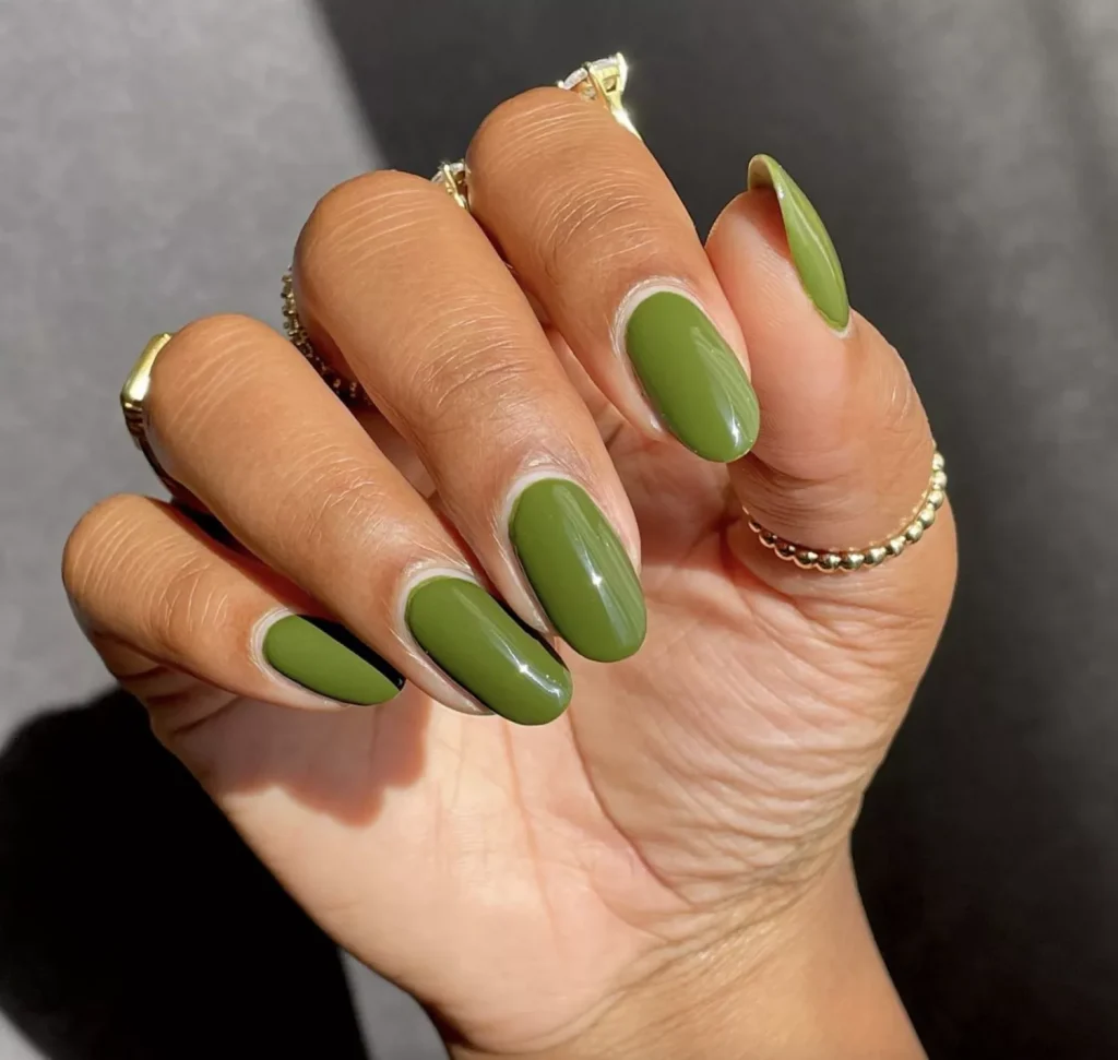 Mão branca encurvada com anel e unha verde oliva