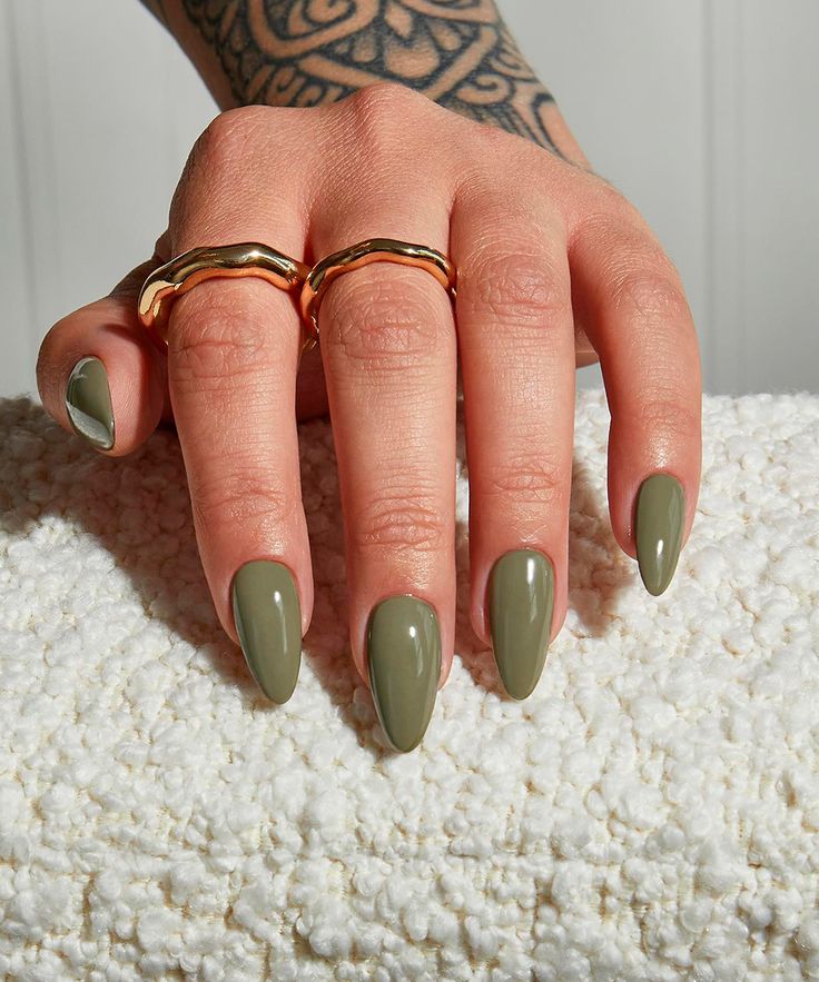 Mão branca, apoiada, com anéis e esmaltes verde oliva 
