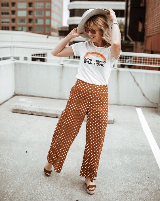 mulher na rua com t-shirt e calça laranja com estampa de poá