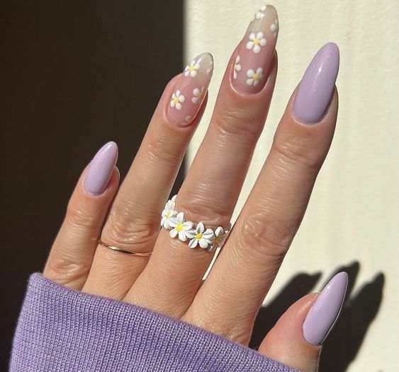 mão com esmalte lilás e anel de flores brancas com amarelo