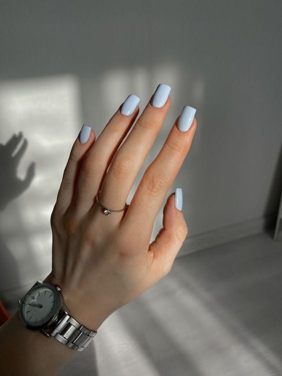 mão com formato de unha quadrado e esmalte azul