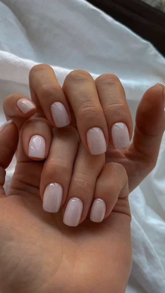 mão com formato de unha quadrado e esmalte branco