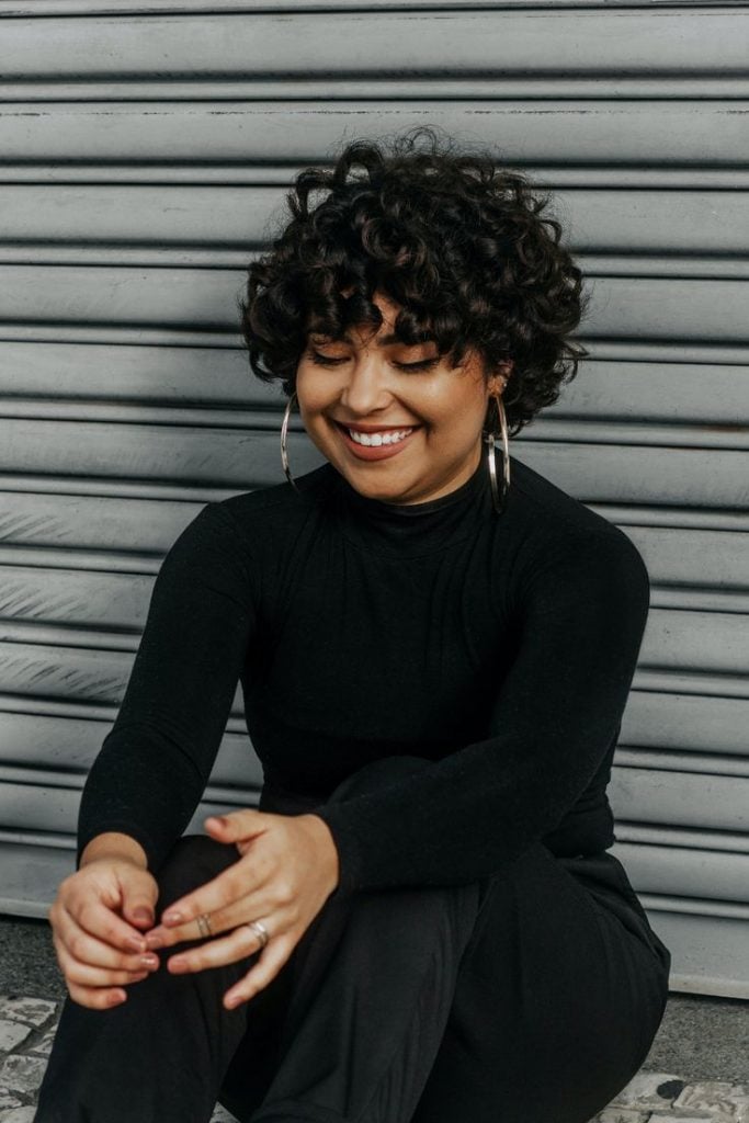 Mulher com cabelo cacheado, curto, preto e com franja reta