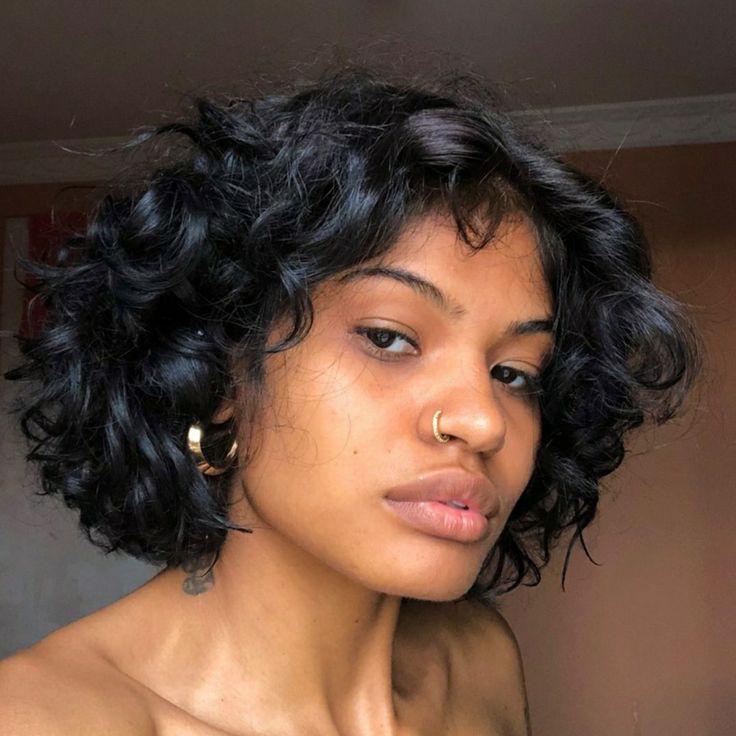 Mulher com cabelo cacheado, curto, preto e com franja cortininha