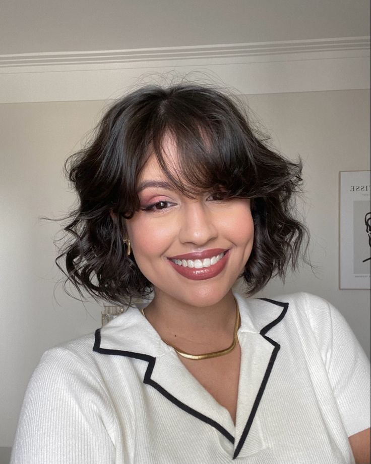 Mulher branca e jovem com cabelo curto no estilo bob com franja, usando maquiagem