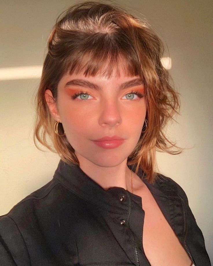 Mulher com jaqueta preta e cabelo curto liso com franja 