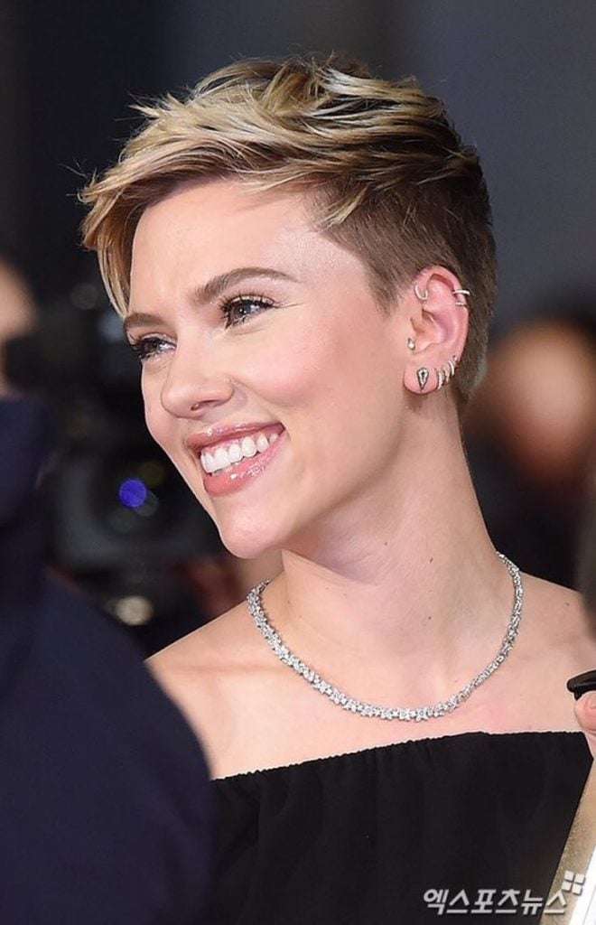 Mulher branca sorrindo com o cabelo curto liso estilo pixie