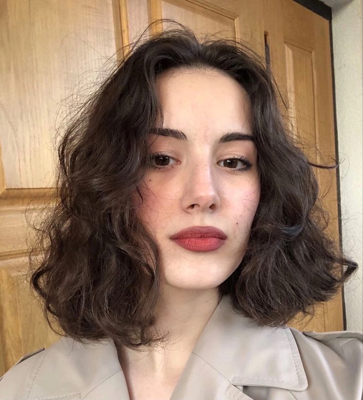 Mulher branca e jovem com cabelo curto no estilo french bob, usando batom vermelho