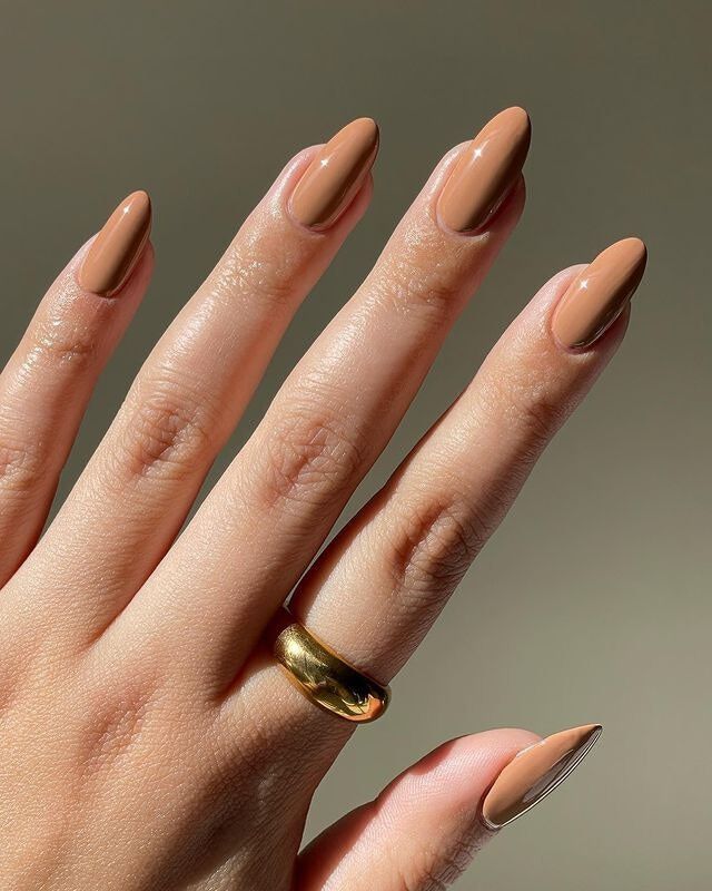 Mão branca com anel dourado e unha marrom clarinho
