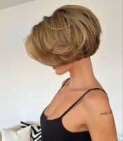 Mulher com cabelo loiro, com mechas, curto, em estilo chanel, com franja longa e em camadas