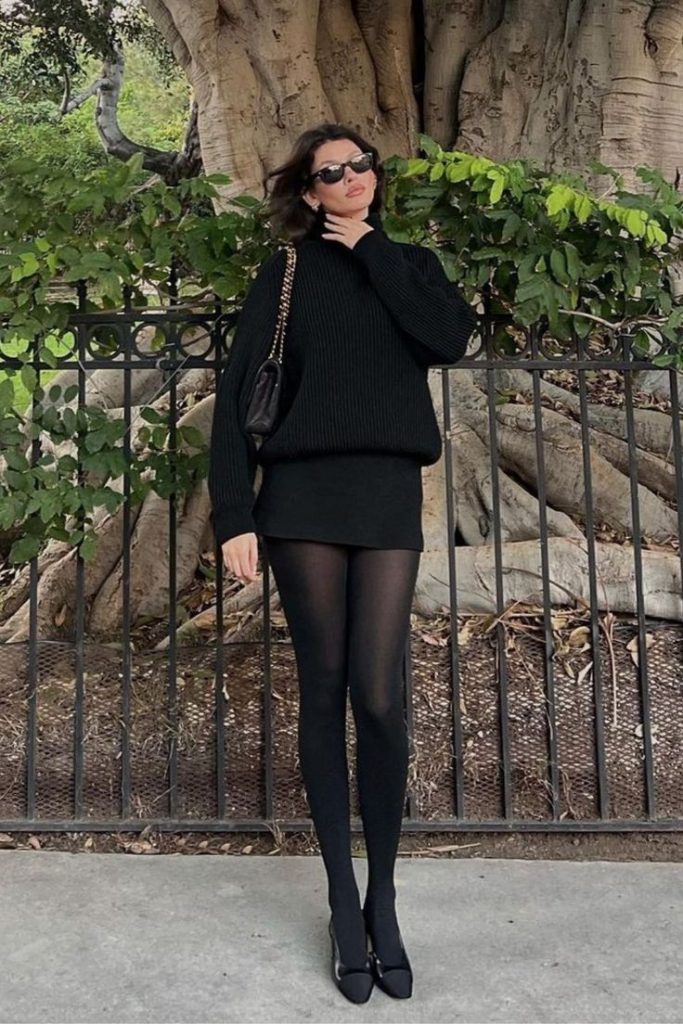 Mulher na frente de uma cerca com look all black e sapatilha preta