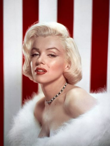 Marylin Monroe com vestido de plumas, colar de brilhantes e bob barroco