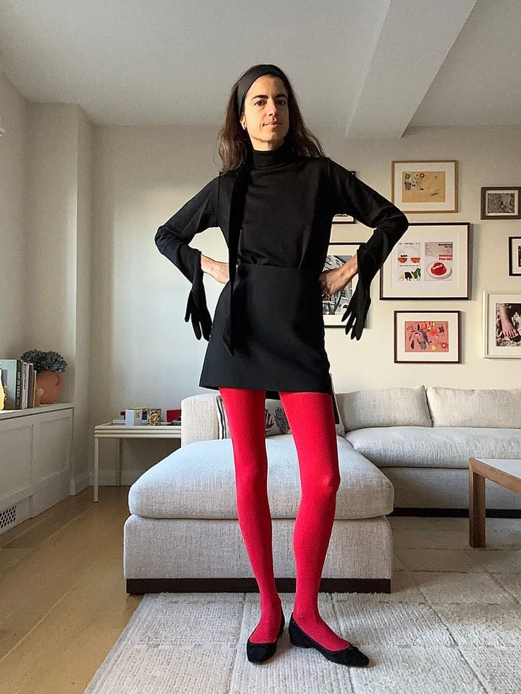 Mulher com look preto, meia-calça vermelha e sapatilha 