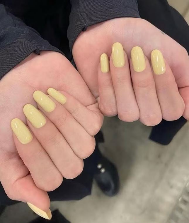 Mão brancas encurvadas com unha amarelo manteiga
