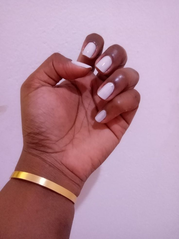 Mão negra com bracelete dourado, e unha branca