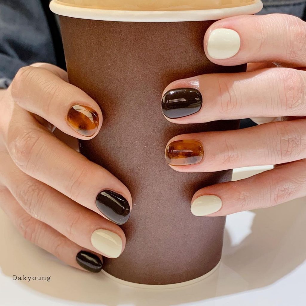 Mãos com chocolate nail segurando um copo de papelão marrom