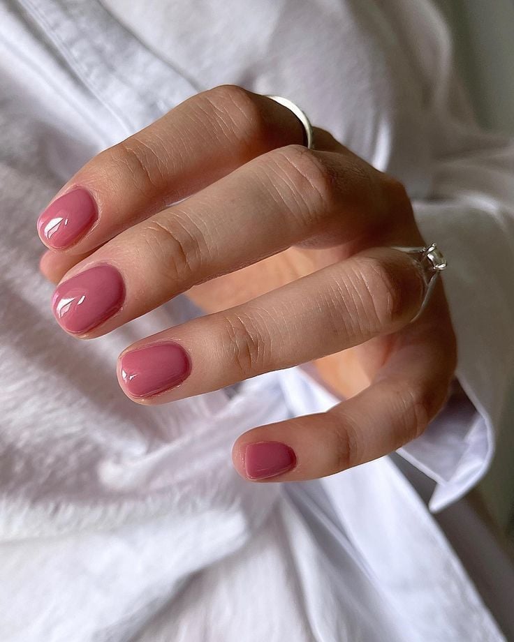 Mão branca curvada com anéis e unha rosa