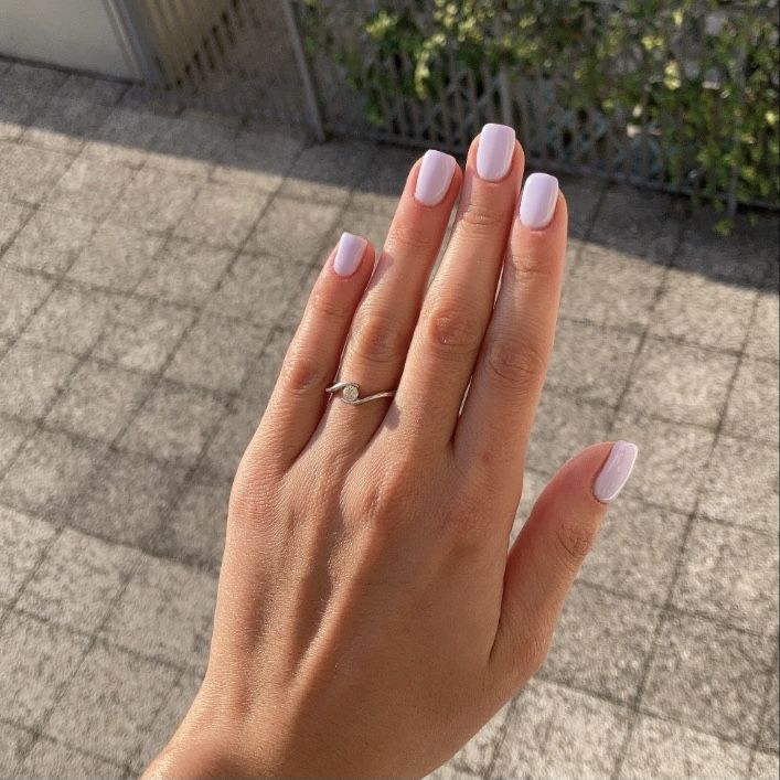 Mão branca com anel e unha lilás