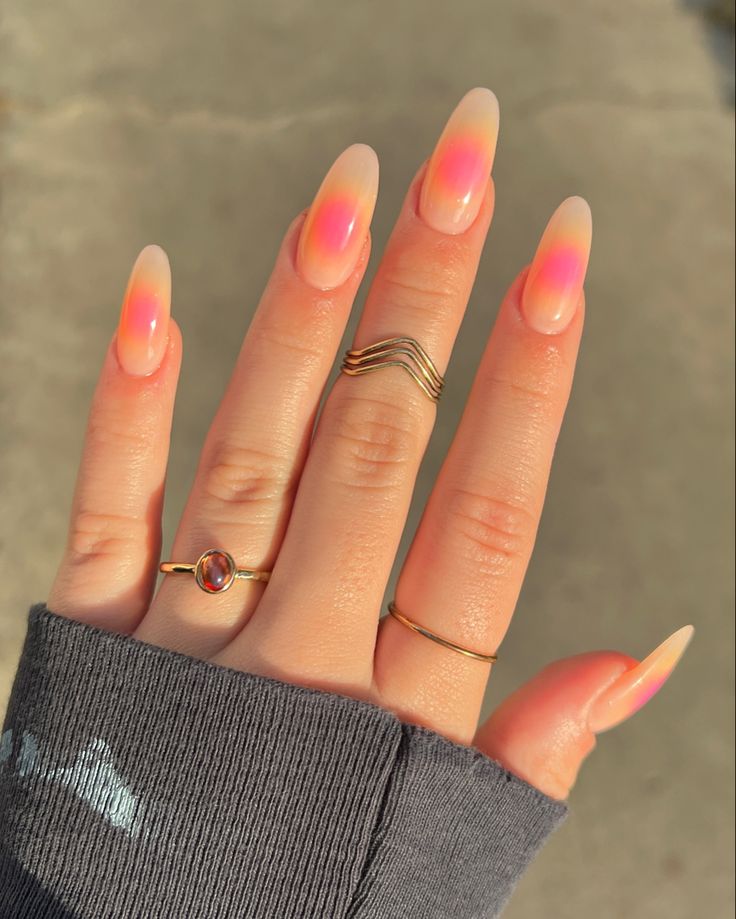 Mão branca com manga cinza, anéis e aura nail rosa