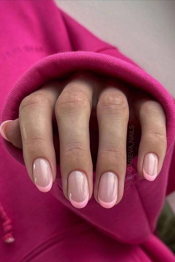Mão branca com manga rosa e unha francesinha rosa