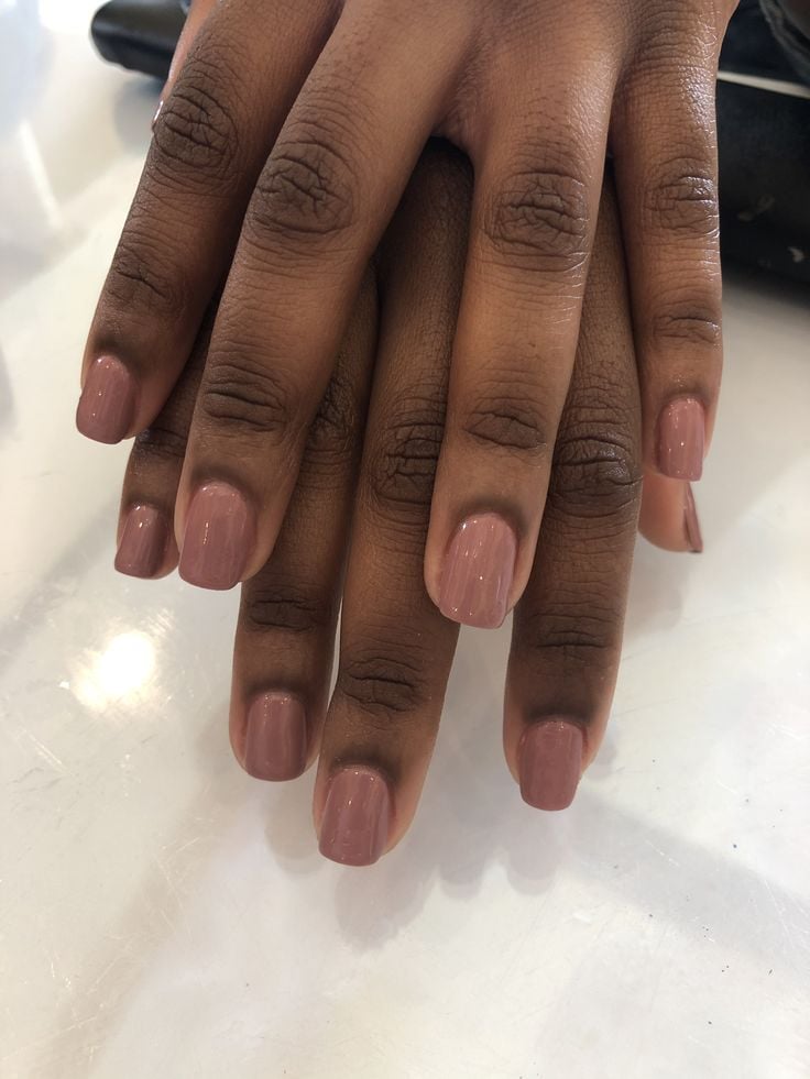 Mãos negras sobrepostas com unha nude
