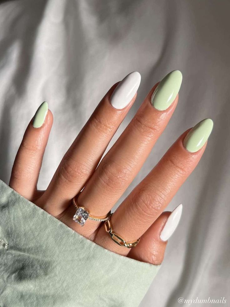 Mão branca com manga verdinha, anéis dourados e unha verde menta com branco 