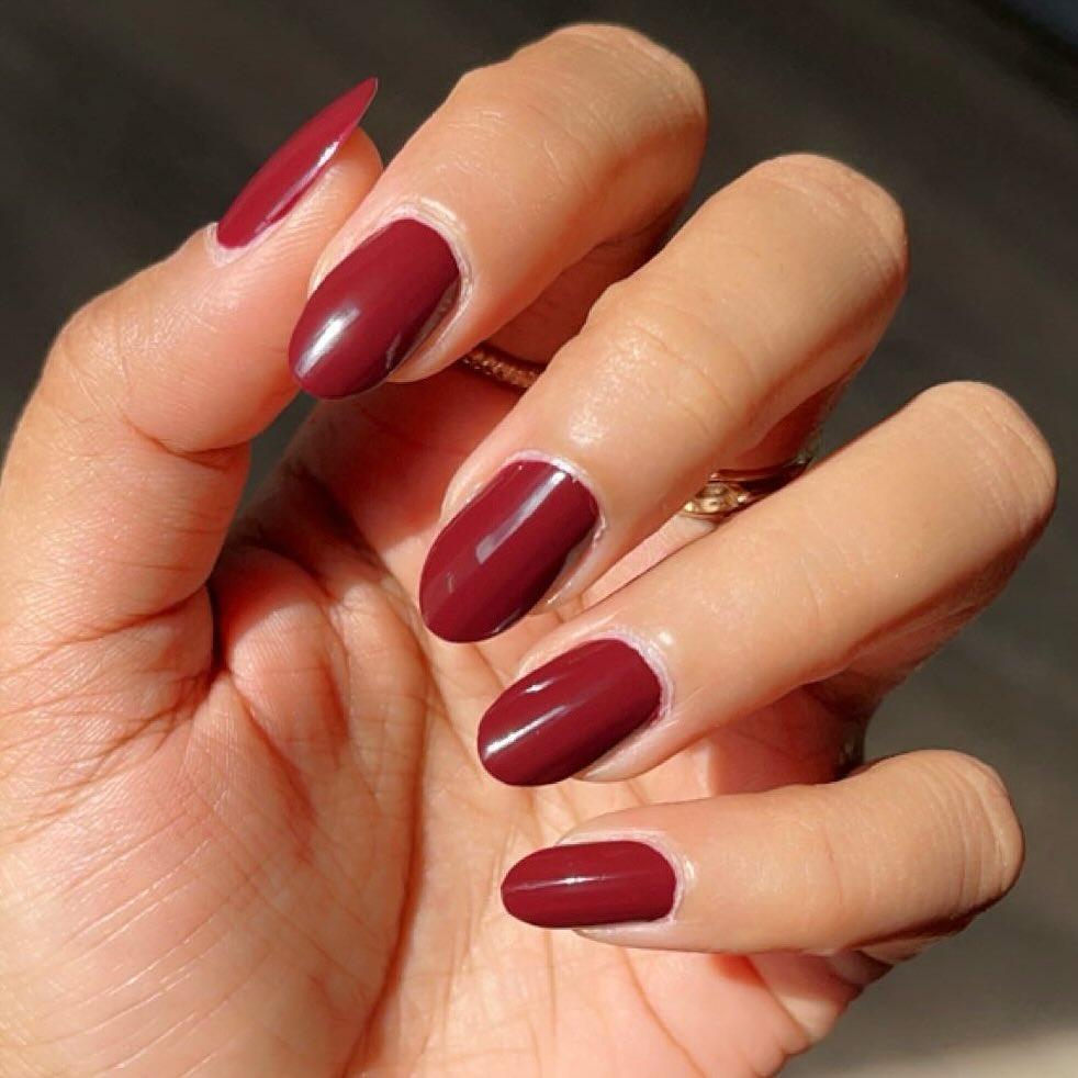 Mão branca encurvado com unha vermelho cereja