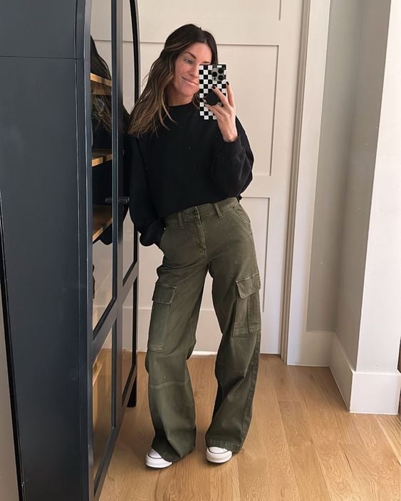 Mulher usando suéter preto, calça cargo verde e tênis all-star
