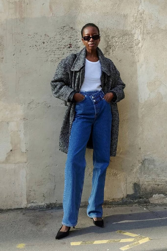 Mulher usando regata branca, casaco midi e calça jeans com scarpin