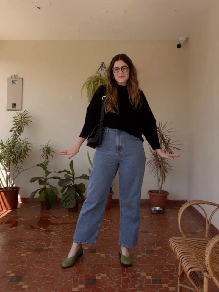 Mulher usando suéter preto e calça jeans de lavagem clara