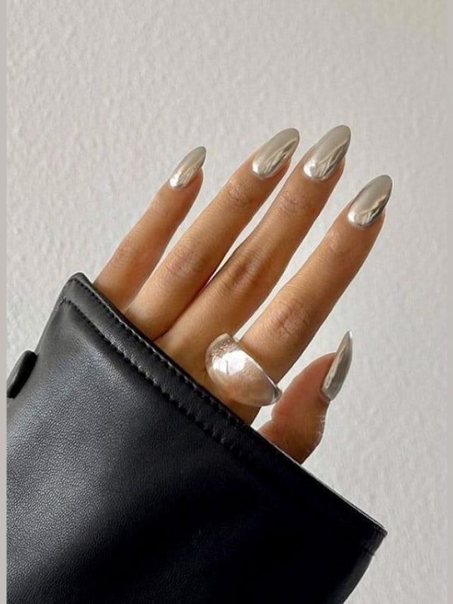 Mão branca colorida com esmalte marrom na estética cromada em metalizado
