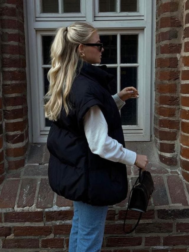 Mulher usando colete puffer preto e calça jeans de lavagem clara