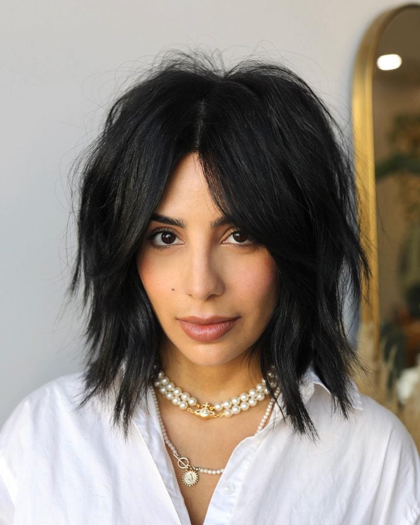 Mulher com cabelo curto, preto, desfiado e com franja