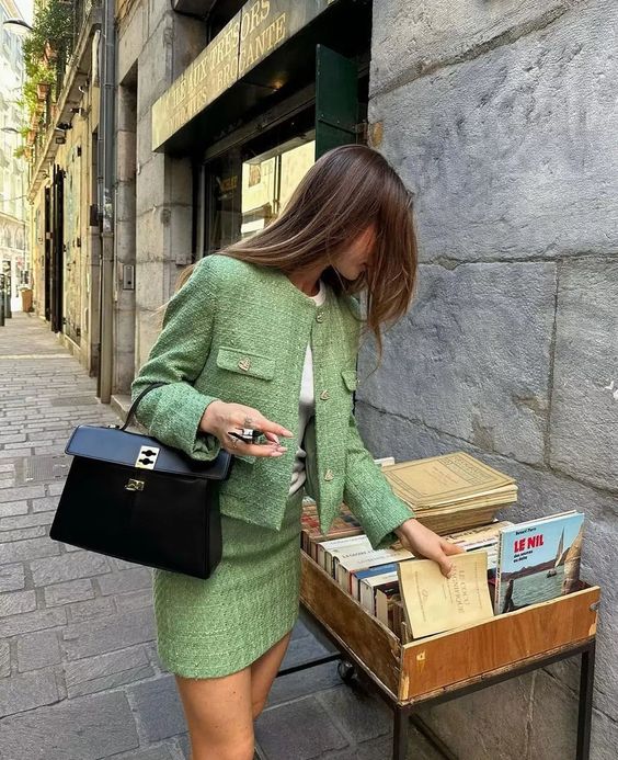 Mulher usando casaco de lã verde mexendo em livros