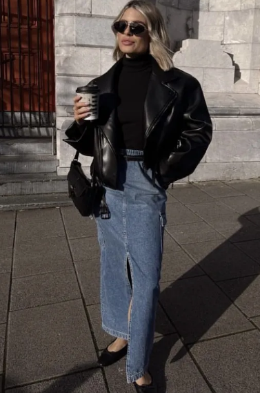 Mulher usando jaqueta preta e saia jeans longa com sapatilha preta