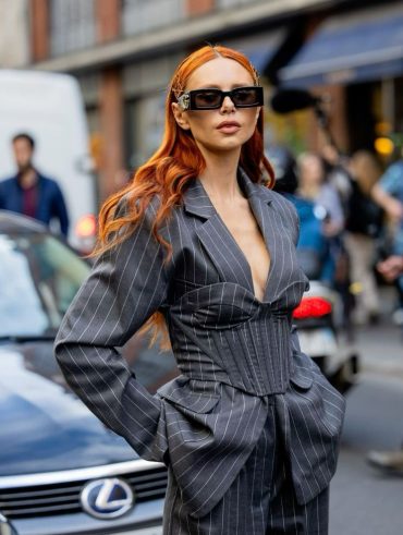 Mulher ruiva, com óculos escuros e conjunto com estampa risca de giz