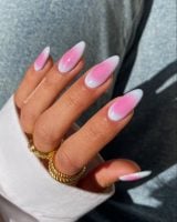 Mão branca curvada com anéis e unha aura com verde e rosa