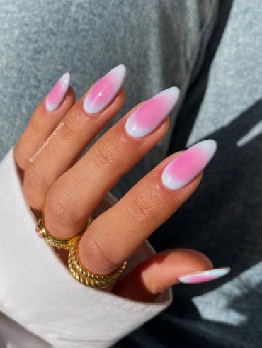 Mão branca curvada com anéis e unha aura com verde e rosa